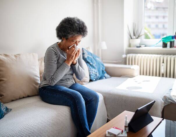 femme âgée se mouchant assise sur sofa