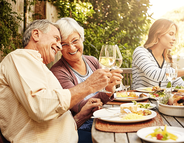 Elderly couple chinning a glass of wine at dinner table