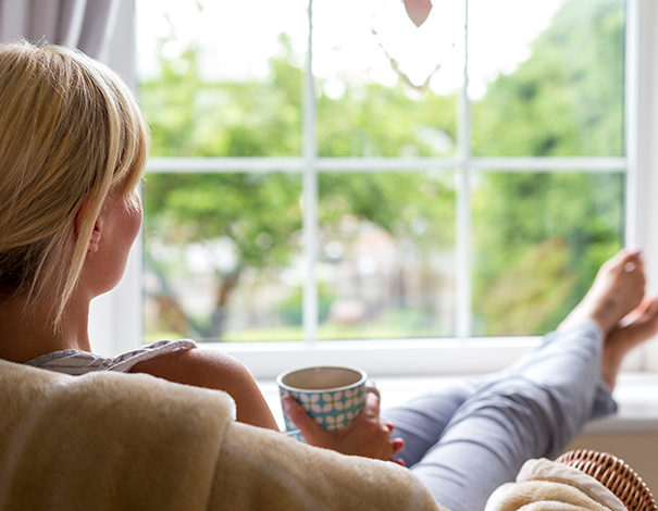 Woman sitting on chair with feet on window ledge