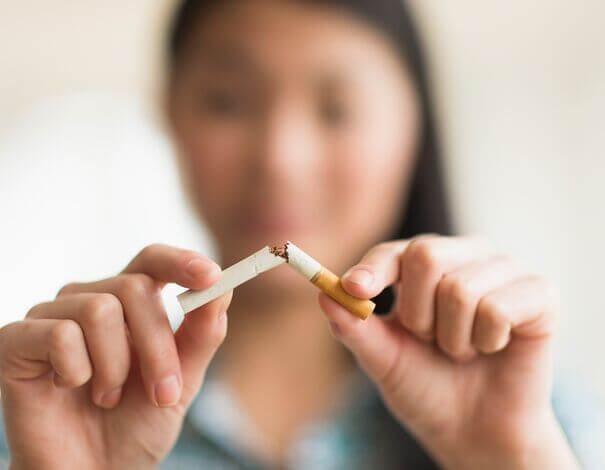 Woman holding cigarette and breaking it