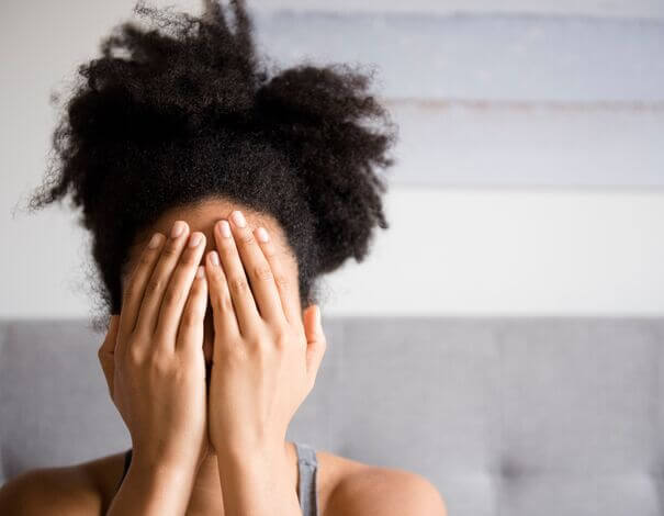 Woman who hides her face with her hands