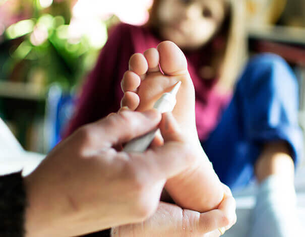 Hand applying wart medication on girl's foot