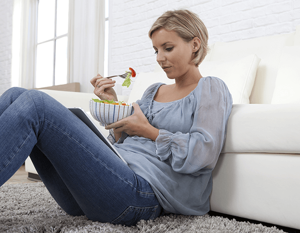 Femme assise au sol mangeant un bol de fruits