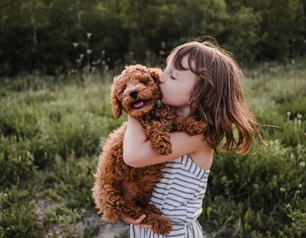 Fillette a l'extérieur tenant dans ses bras et embrassant un chiot