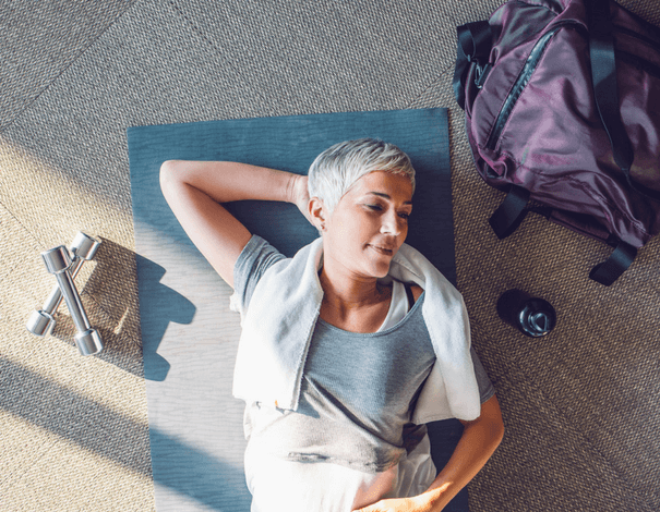 Femme âgée couchée au sol sur un tapis d'exercice