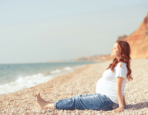 Femme enceinte assise sur la plage Femme enceinte assise sur la plage