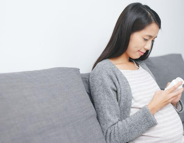 femme enceinte lisant étiquette d'une bouteille de médicaments femme enceinte lisant étiquette d'une bouteille de médicaments