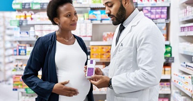 femme enceinte se faisant conseiller sur des médicaments par un pharmacien
